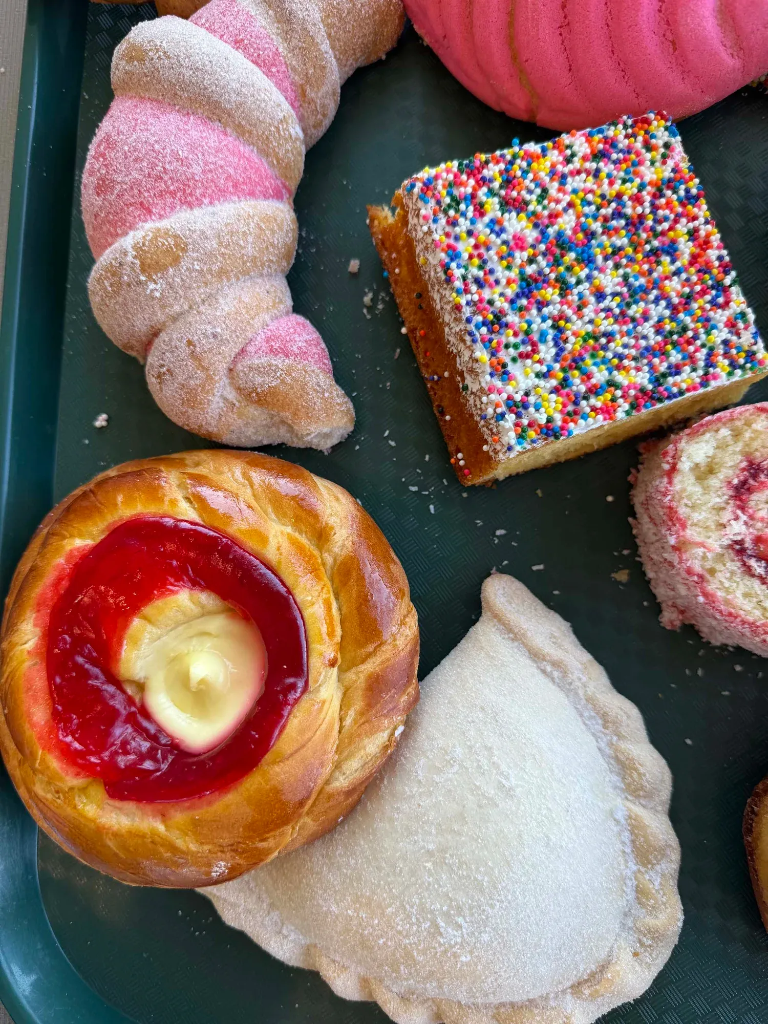 Sugar-dusted empanada on a tray of pan dulce